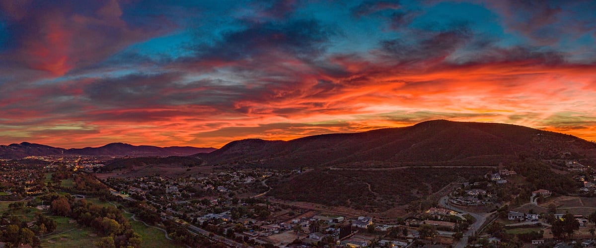 A sunset over a mountainous landscape with a town in the foreground.