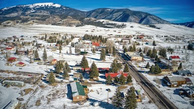 Un pueblo cubierto de nieve con una vía de tren, rodeado de montañas y pinos.