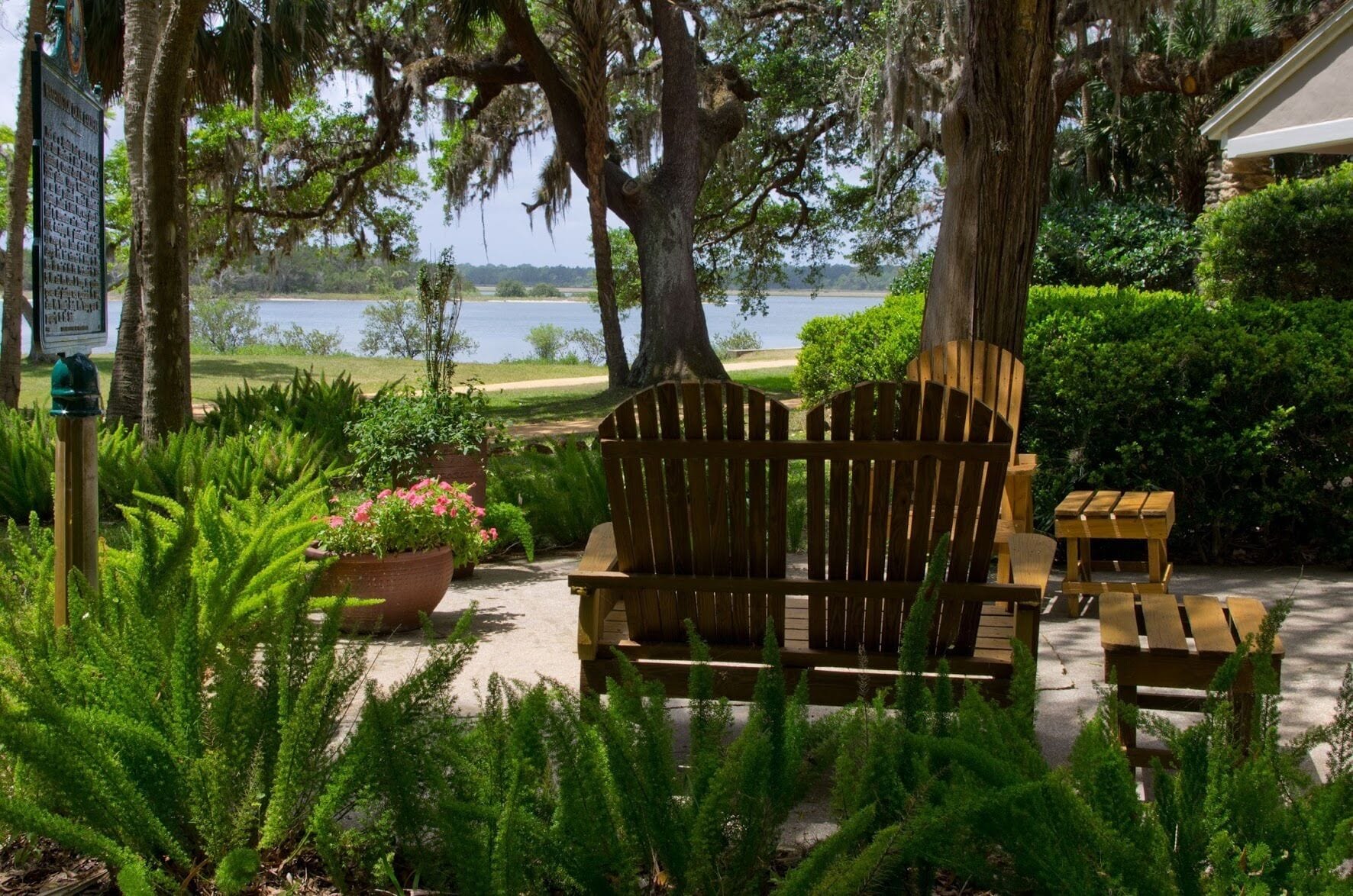 A wooden bench and table set in a garden with a view of a lake.