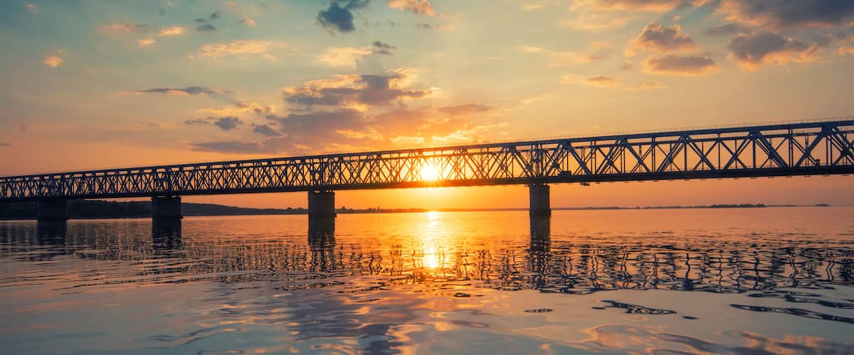 Un pont enjambant une étendue d'eau calme au coucher du soleil.