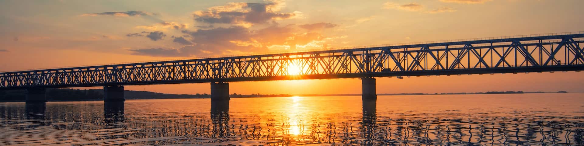 A bridge over a calm body of water at sunset.