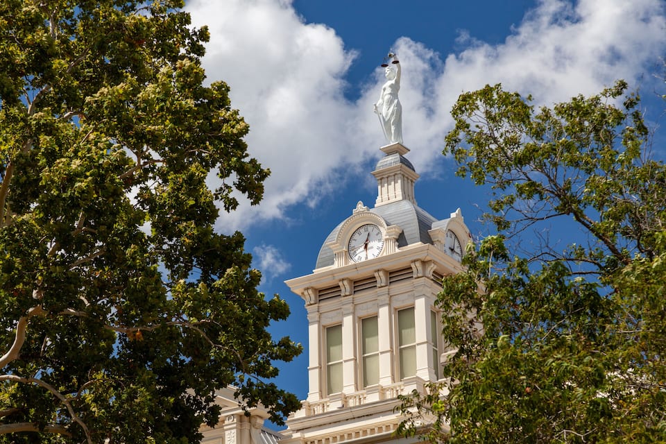A building with a clock tower and a statue on top.