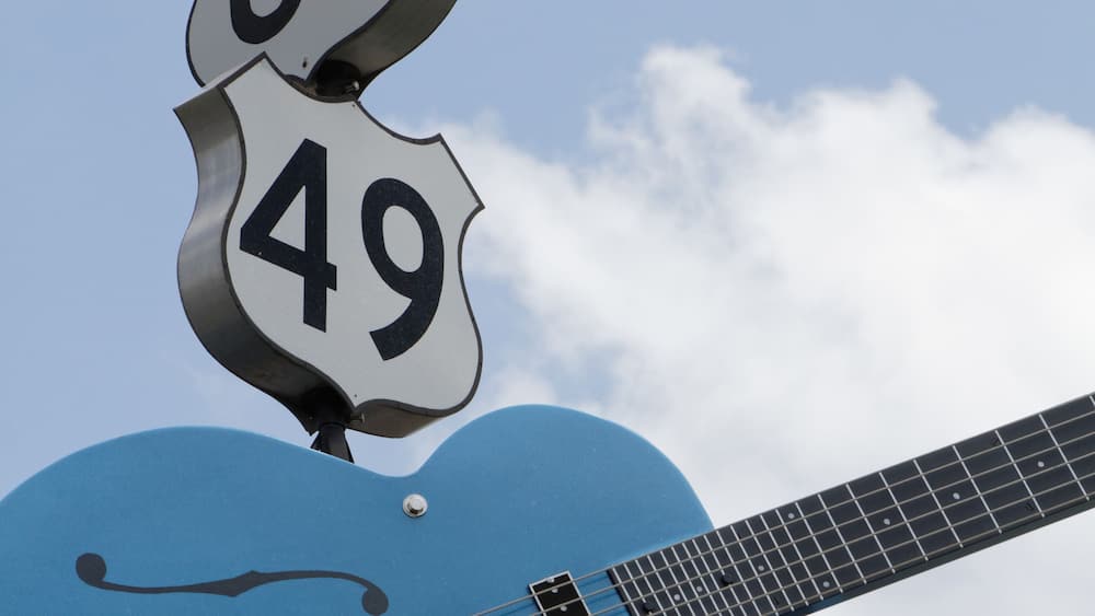 A blue guitar with road signs 61 and 49 mounted on top.
