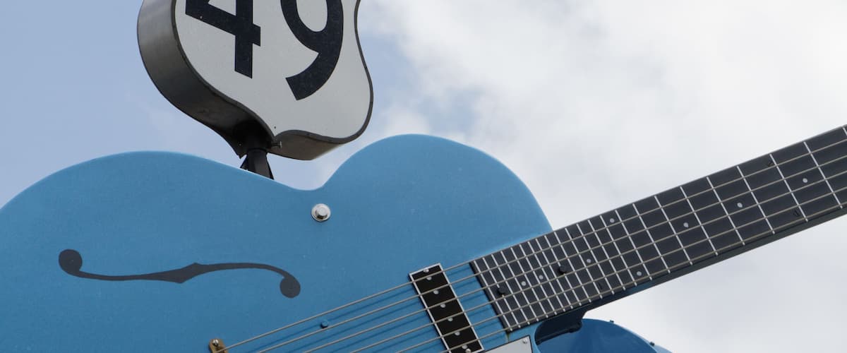 Een blauwe gitaar met verkeersborden 61 en 49 erop bevestigd.