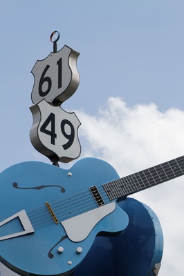 A blue guitar with road signs 61 and 49 mounted on top.