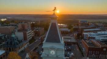 A cityscape with a prominent clock tower, a river, and a sunset in the background.