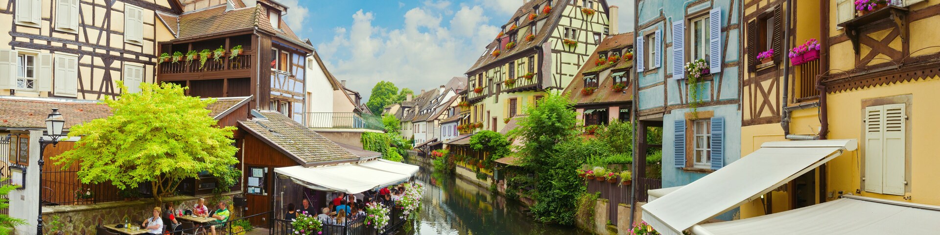 A narrow waterway flanked by traditional half-timbered buildings with balconies and flower boxes.