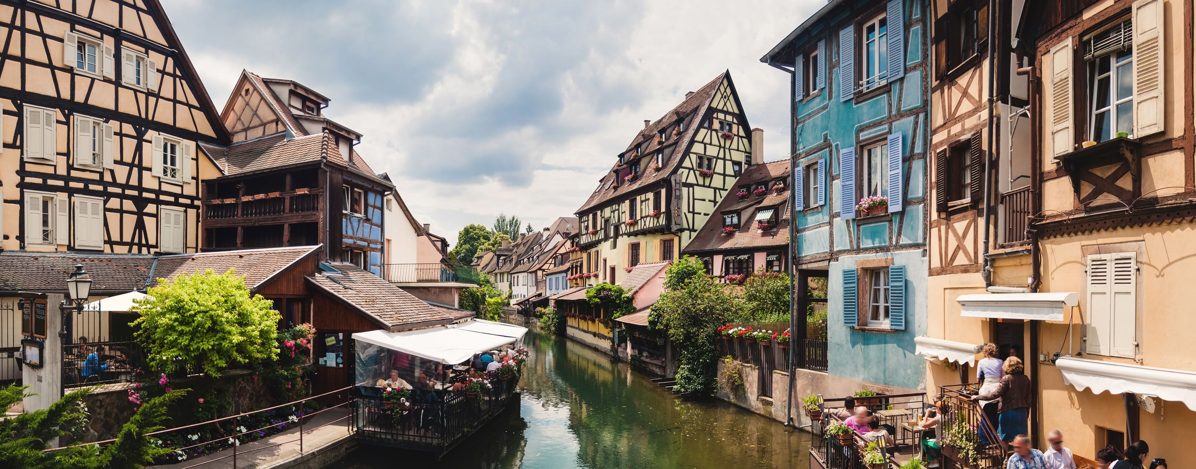 A narrow waterway flanked by traditional half-timbered buildings with balconies and flower boxes.