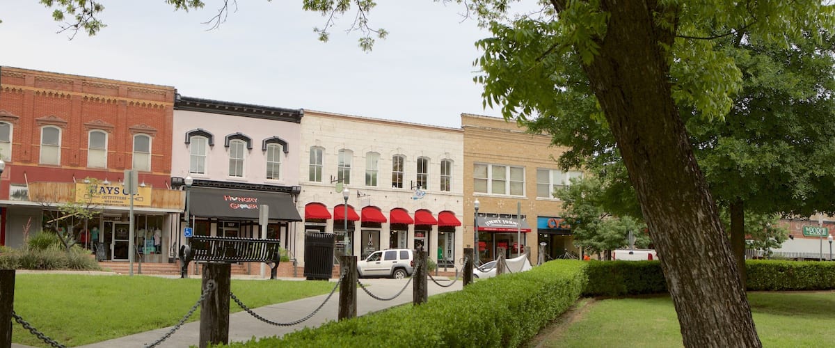 A street lined with historic buildings, a bench, and a tree.