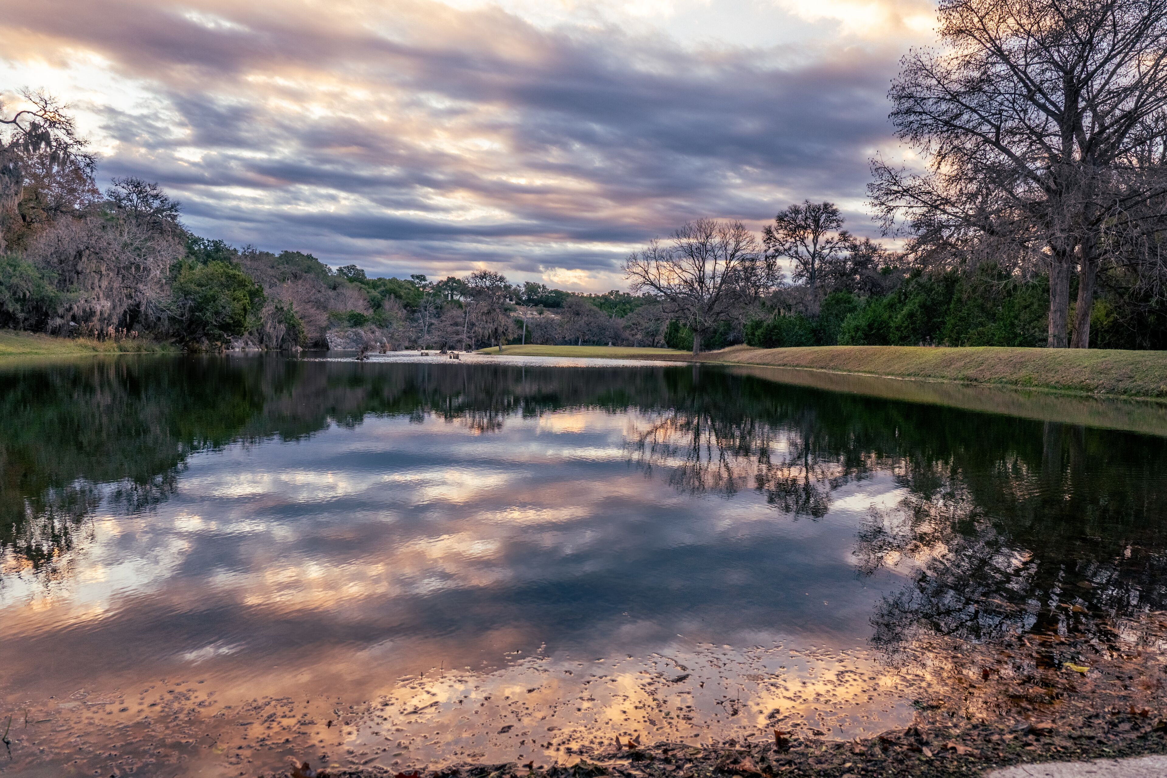 Un lago tranquilo que refleja el cielo y los árboles circundantes.
