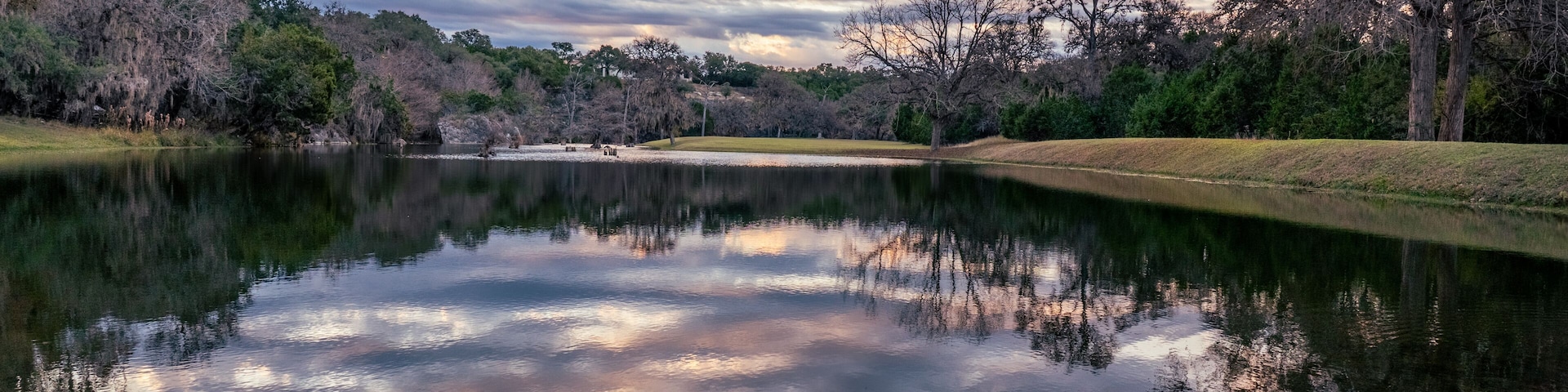 Un lago tranquilo que refleja el cielo y los árboles circundantes.
