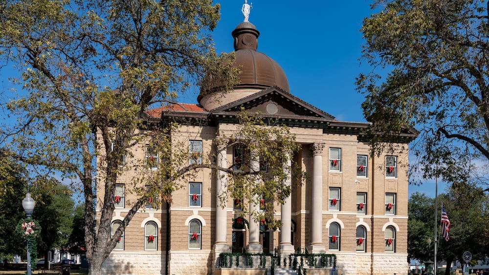 A historic building with a dome and columns, adorned with holiday decorations.