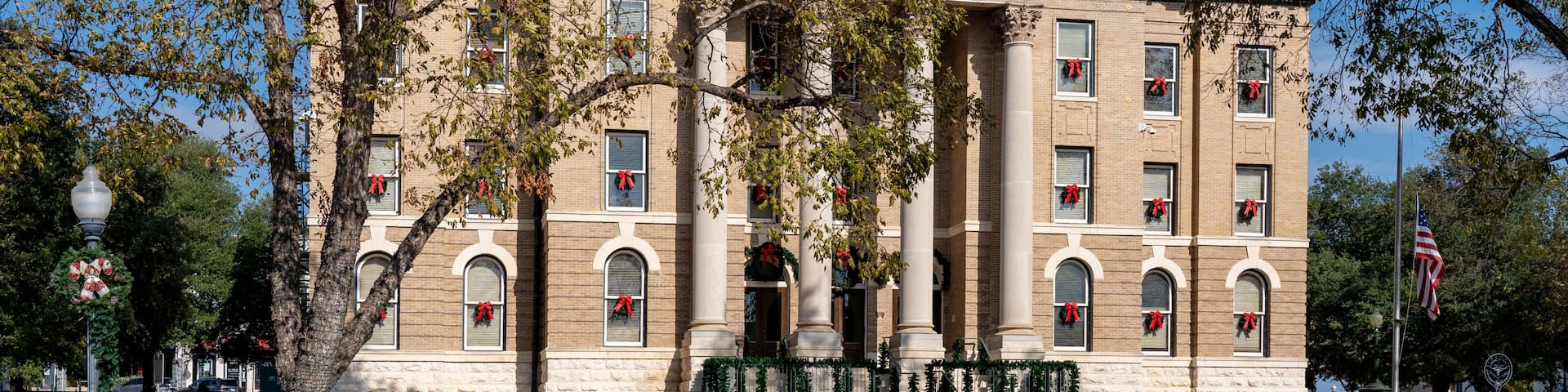 A historic building with a dome and columns, adorned with holiday decorations.