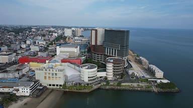 A coastal cityscape with modern buildings, a marina, and a view of the sea.