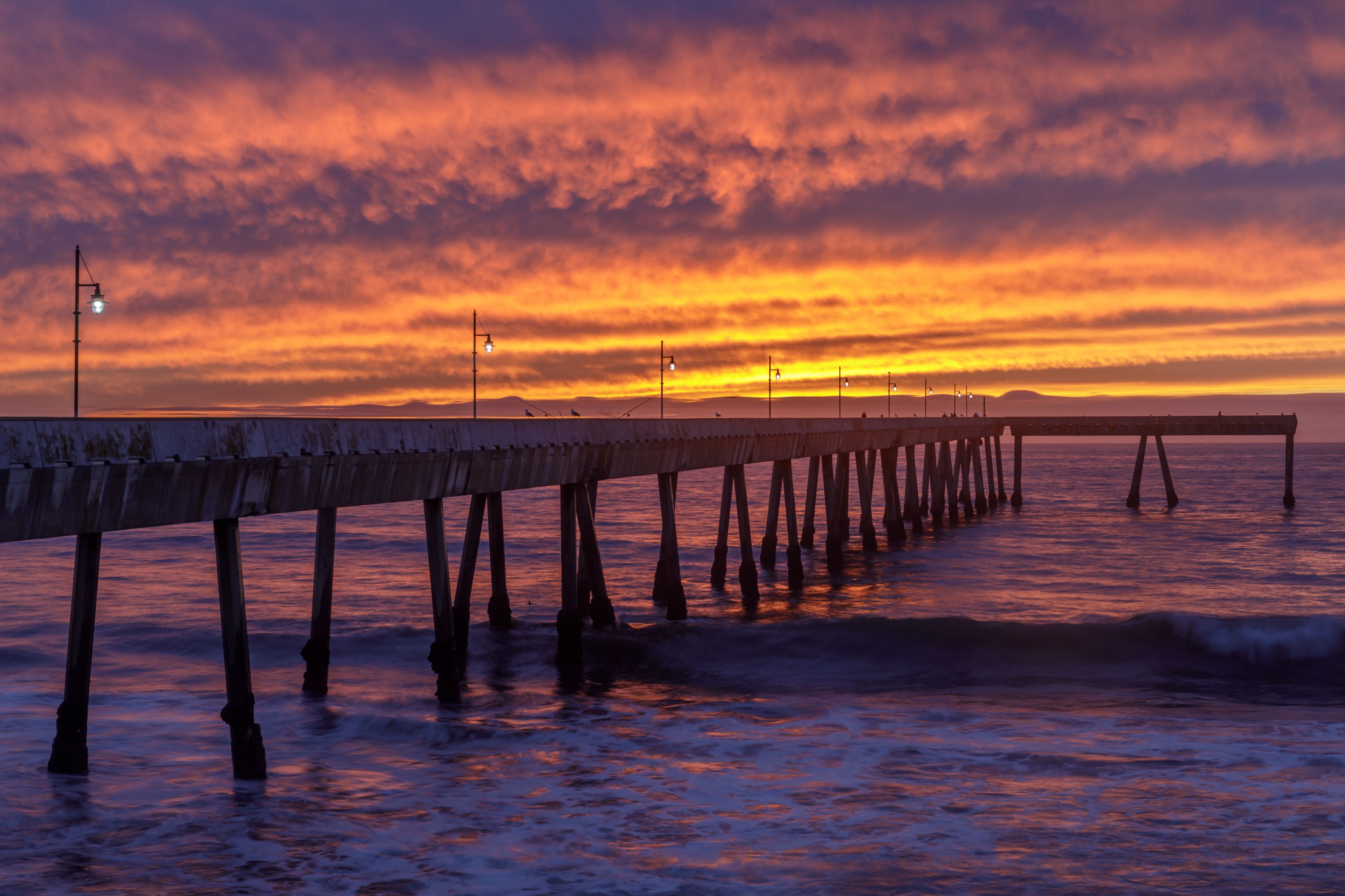 A pier extending into the water with a sunset in the background.