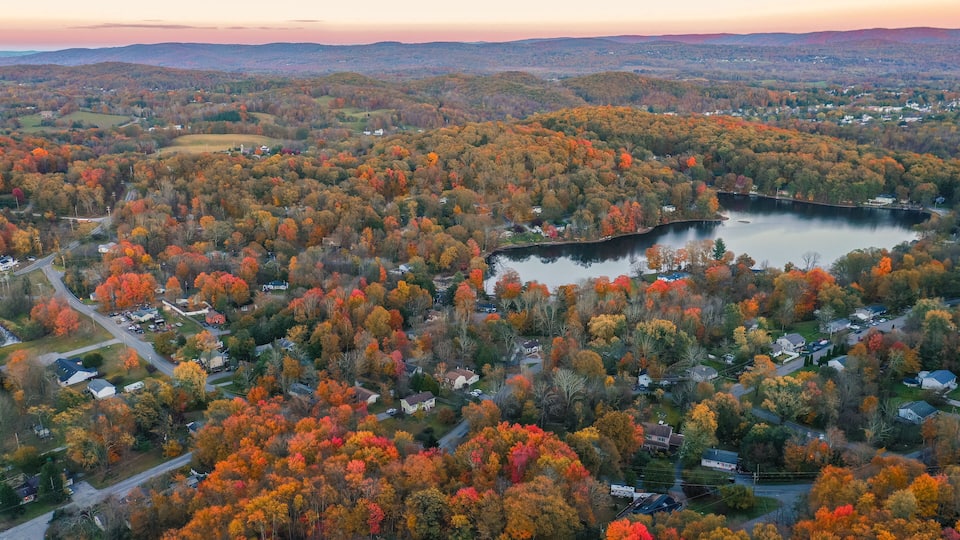 A rural landscape with a lake surrounded by autumn-colored trees and scattered houses.