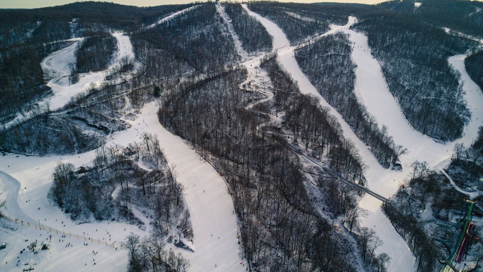 A snow-covered ski slope with multiple trails and a ski lift.
