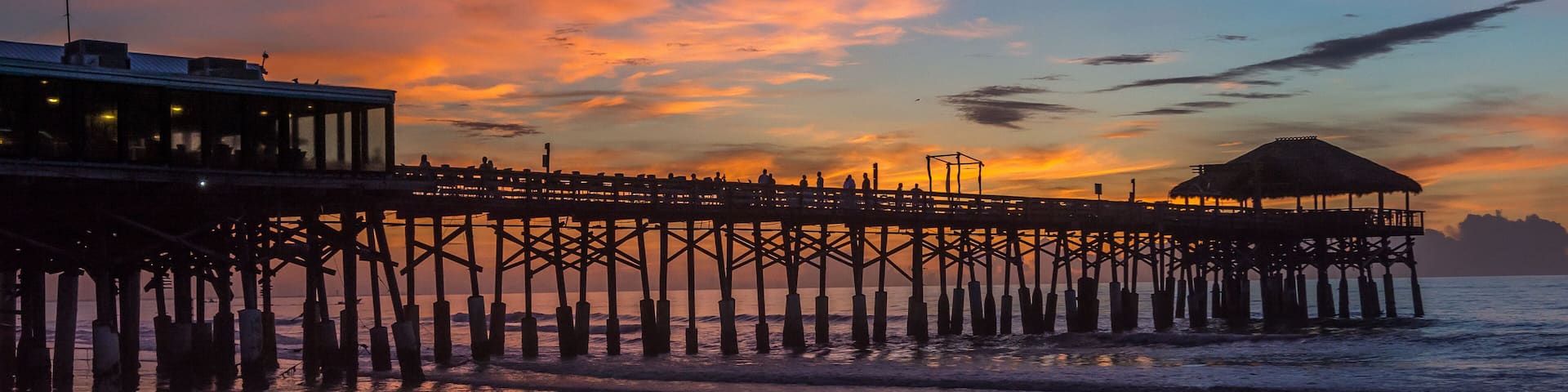 A pier extending into the water with a sunset in the background.