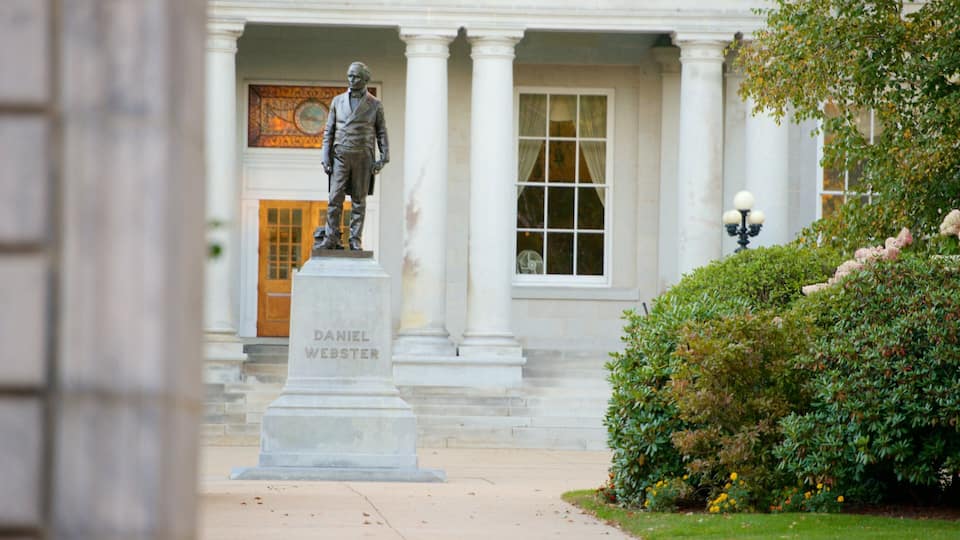 A statue of Daniel Webster on a pedestal in front of a building with columns and a window.
