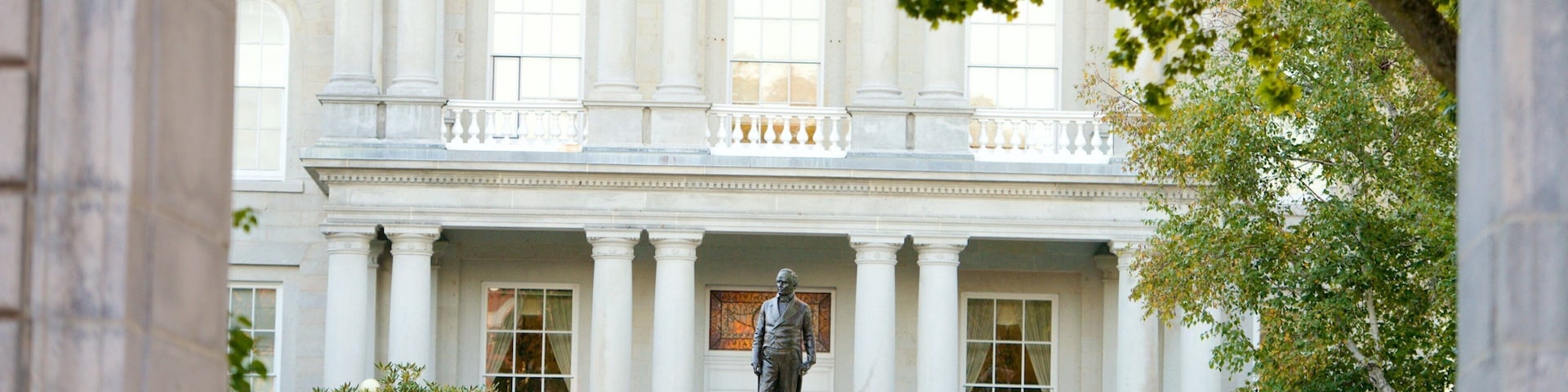 A neoclassical building with a statue of Daniel Webster in front.