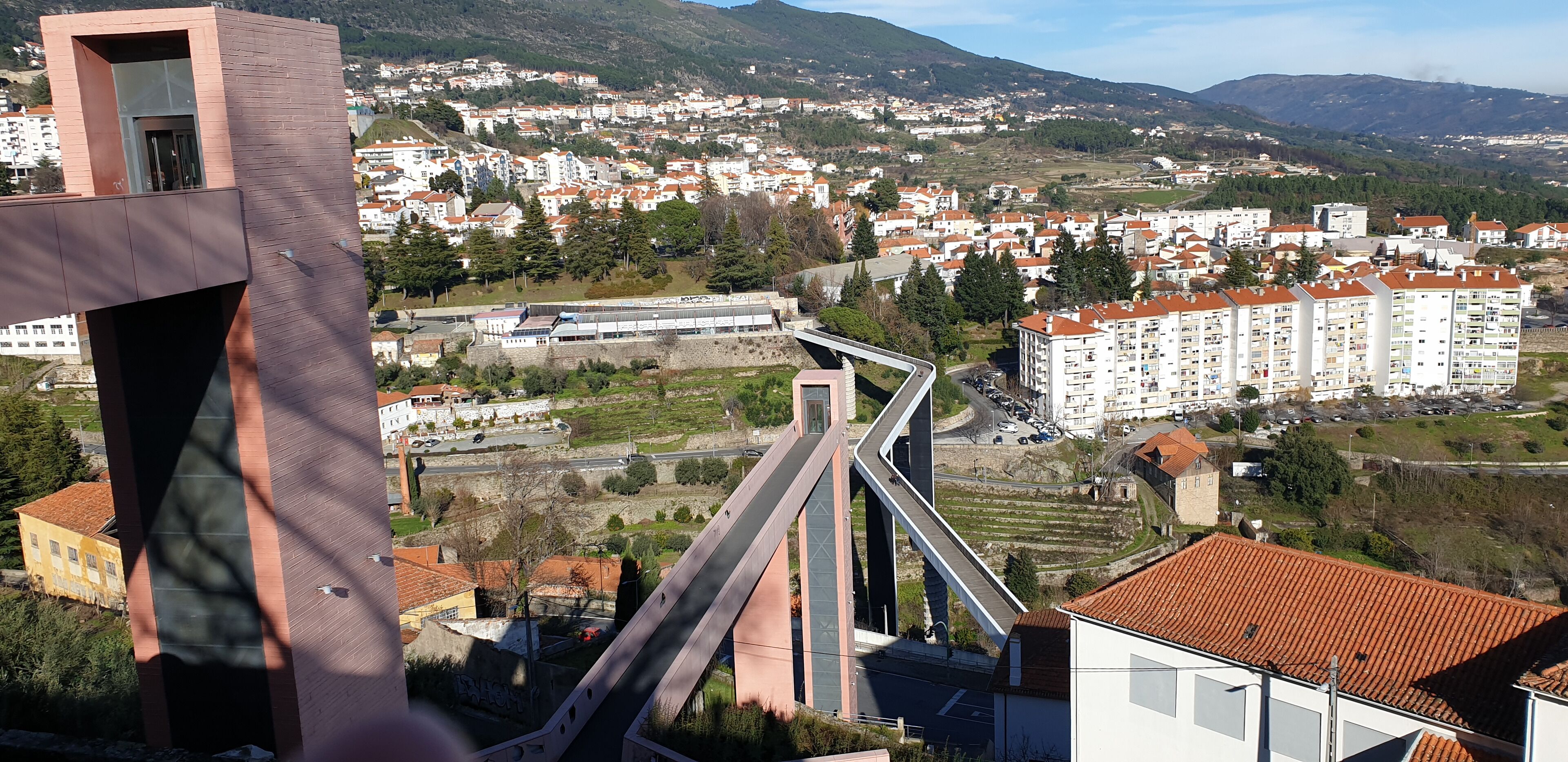 A modern bridge, residential buildings, and a hilly landscape.