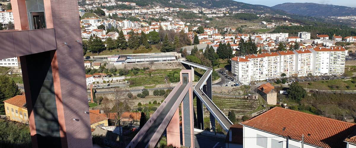 A modern bridge, residential buildings, and a hilly landscape.