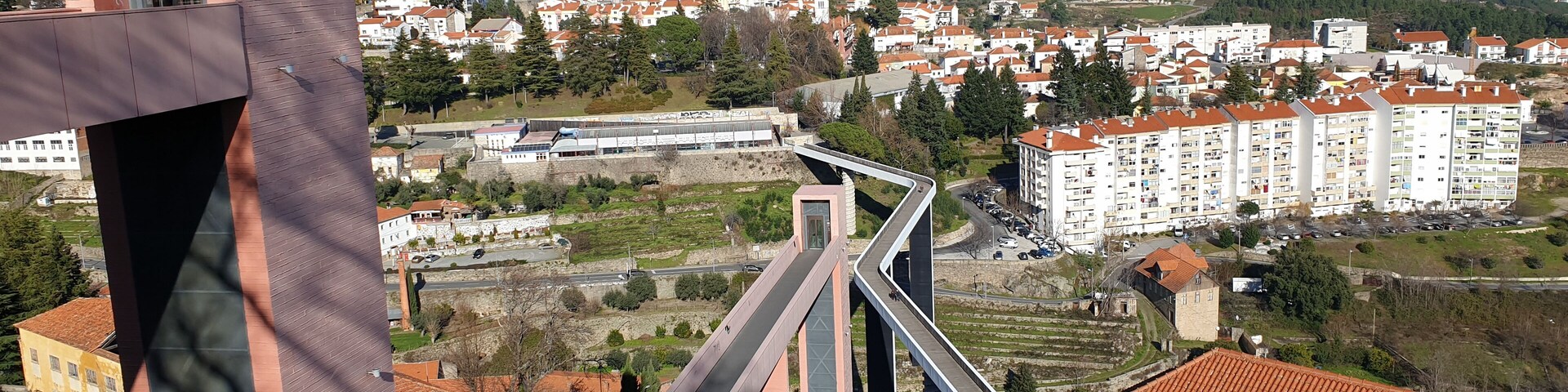 A modern bridge, residential buildings, and a hilly landscape.