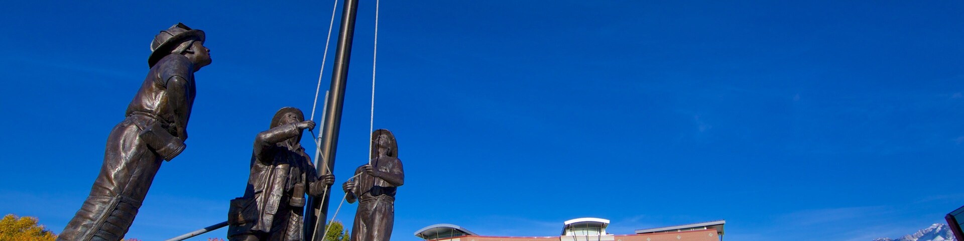 A statue of soldiers with a flagpole and a building in the background.