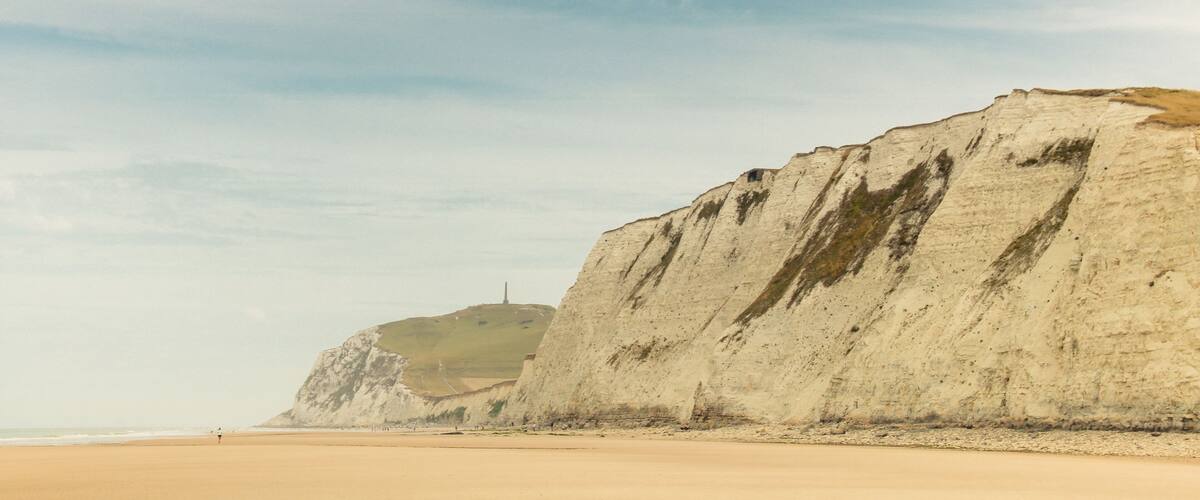 A coastal landscape with a sandy beach and prominent white cliffs.