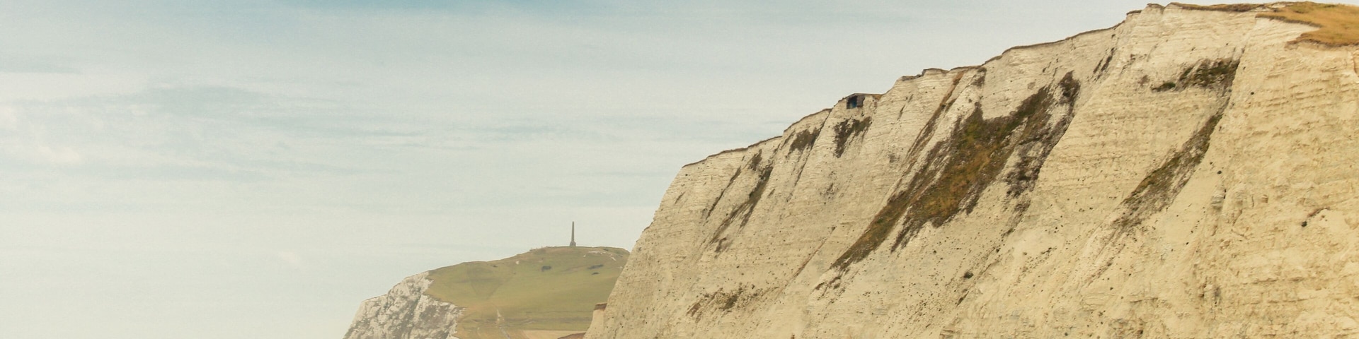 A coastal landscape with a sandy beach and prominent white cliffs.