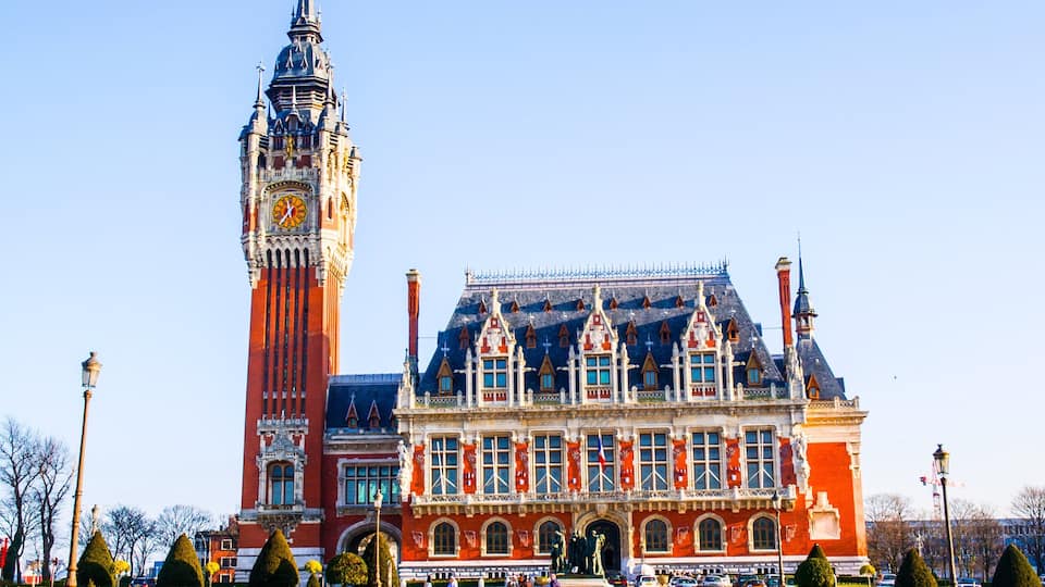 A large clock tower and a historic building with a red facade and ornate architecture.