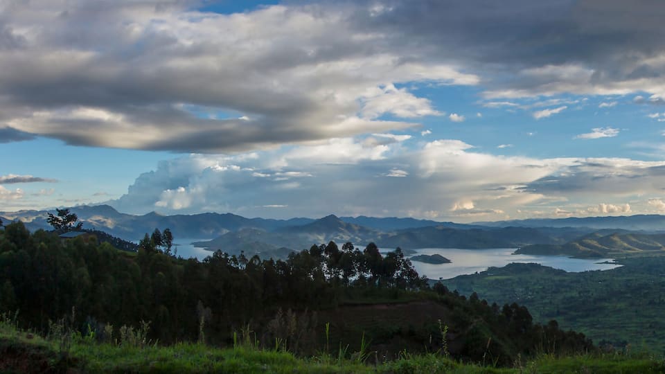 A mountainous landscape with a lake and scattered clouds.