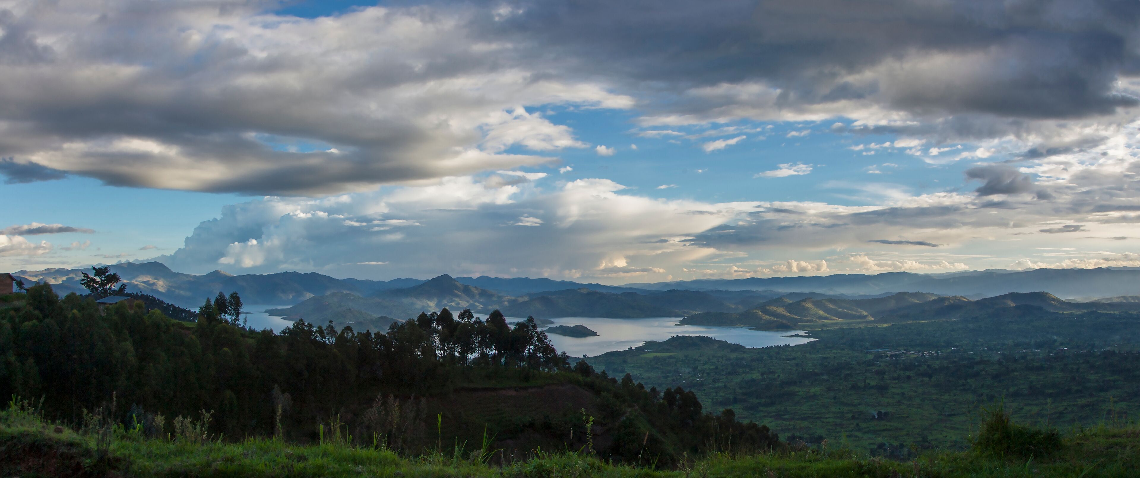 A mountainous landscape with a lake and scattered clouds.