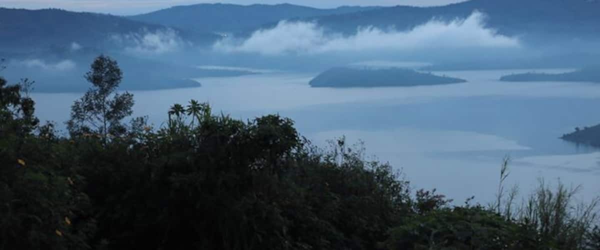 A misty lake surrounded by mountains and dense forest.