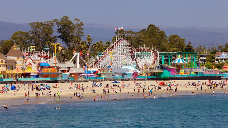 A beach with a Ferris wheel and amusement park rides in the background.