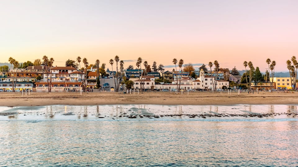 A coastal town with beachfront houses, palm trees, and a sandy beach.