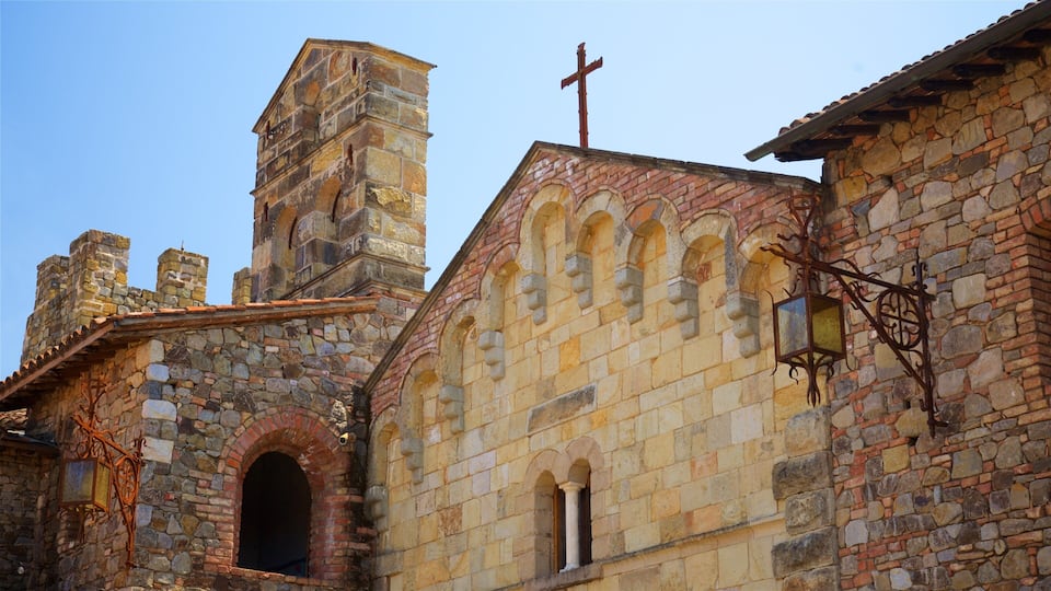 A historic stone church with a cross on top, arched windows, and a bell tower.