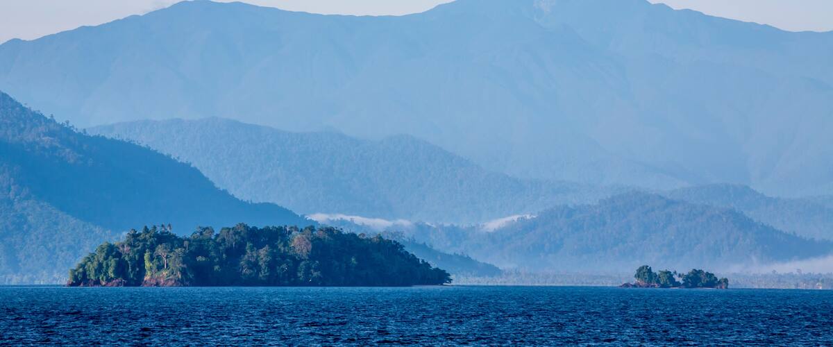 Vista of rainforest covered coast, hills and islands from the Solomon Sea off the shore of Morobe Province, Papua New Guinea; Morobe Province, Papua New Guinea