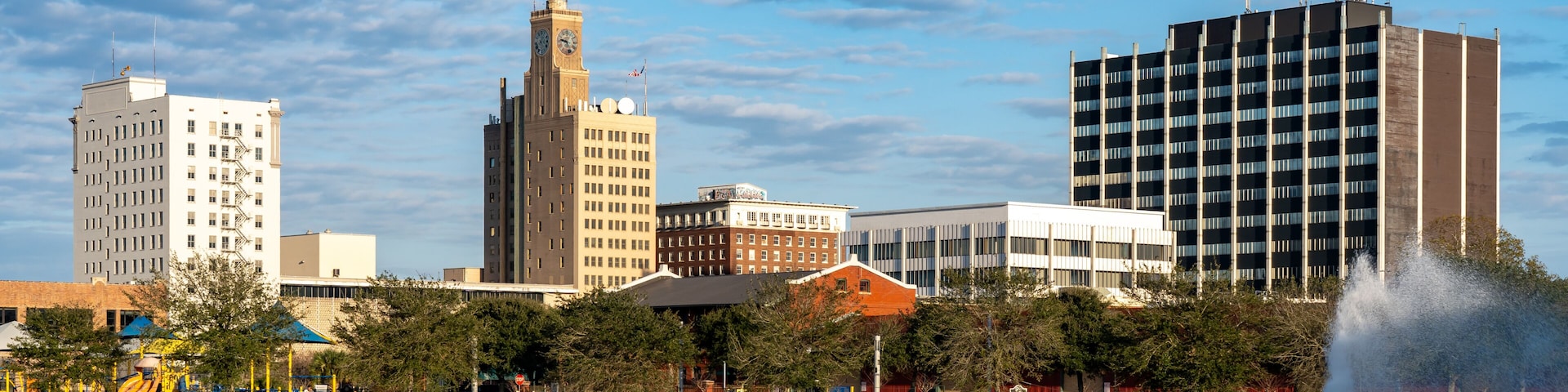 A waterfront cityscape with a variety of buildings, including a clock tower and a modern high-rise.