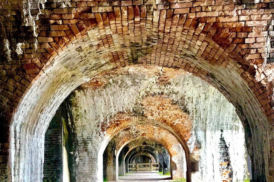 An arched brick corridor with a cobblestone path.