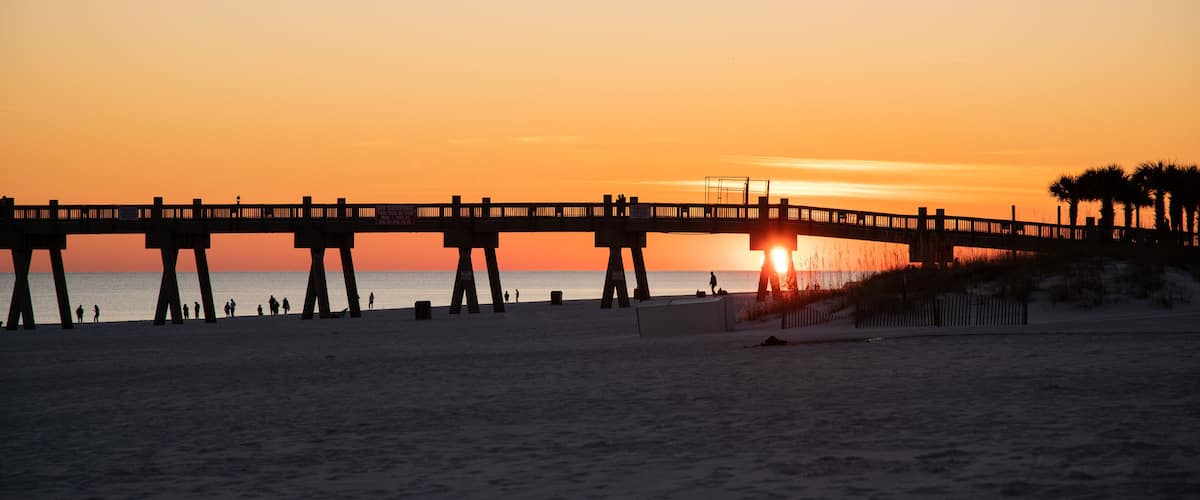 A pier extending over the beach at sunset.