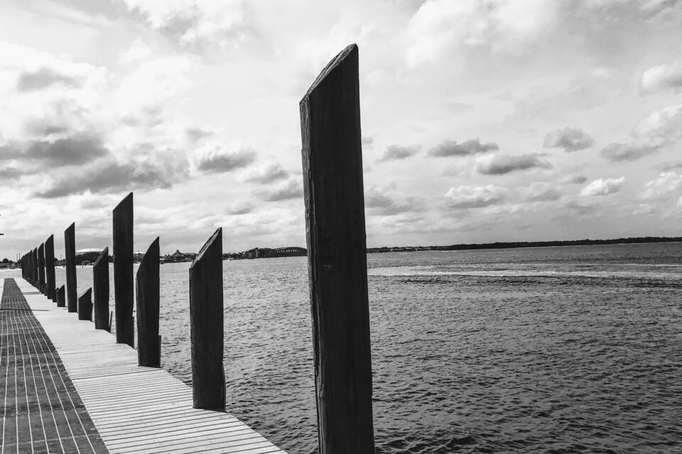 A wooden pier extending into a body of water with a cloudy sky above.