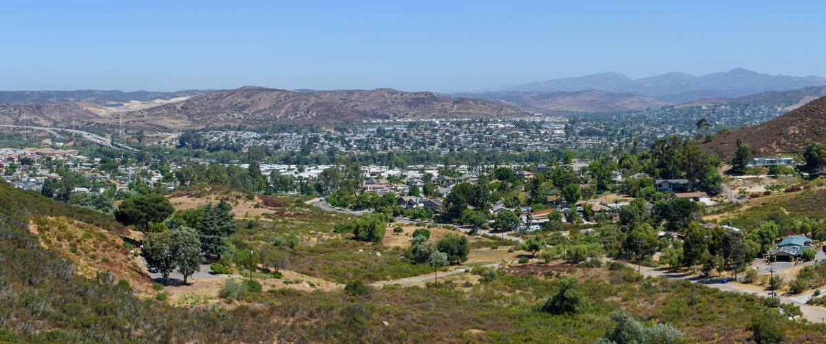 A valley with a town nestled between hills, a winding road, and distant mountains.