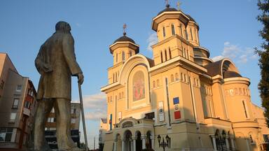 A large church with multiple domes and a statue of a man holding a staff.