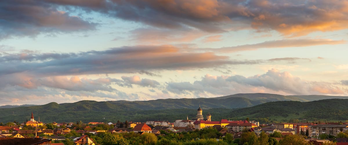 A town with a prominent church and a hilltop tower, surrounded by lush green hills.