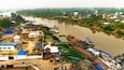 Aerial view of a waterway reflecting the sky, with boats docked along the banks near buildings and lush greenery, Yenagoa, Bayelsa Stae, Nigeria.