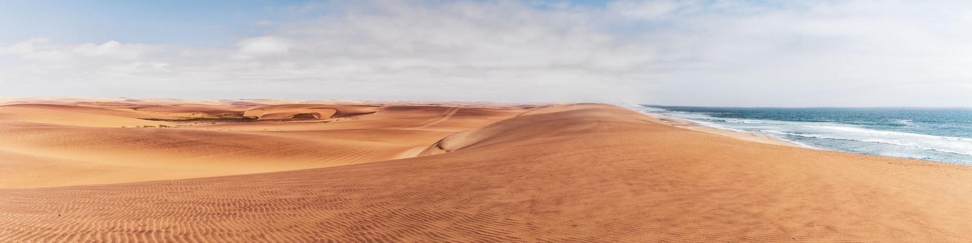 A desert landscape with sand dunes and a beach.