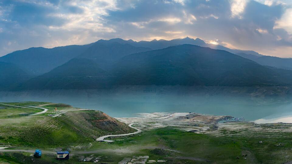 A mountainous landscape with a lake and winding roads.