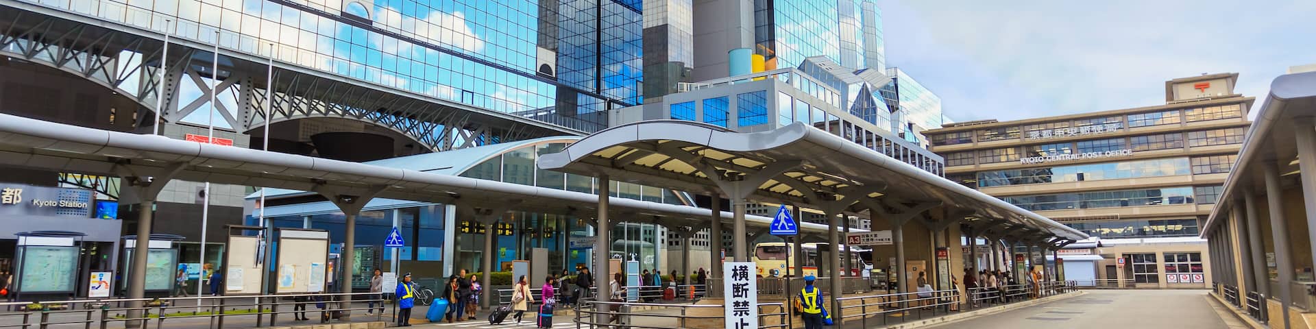 A modern train station with a glass facade and a covered pedestrian walkway.