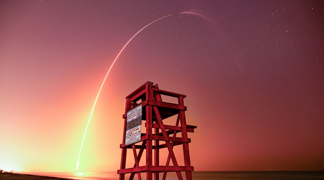 NASA Crew4 & SpaceX rocket launch over beach lifeguard stand at night. Long exposure streak shot